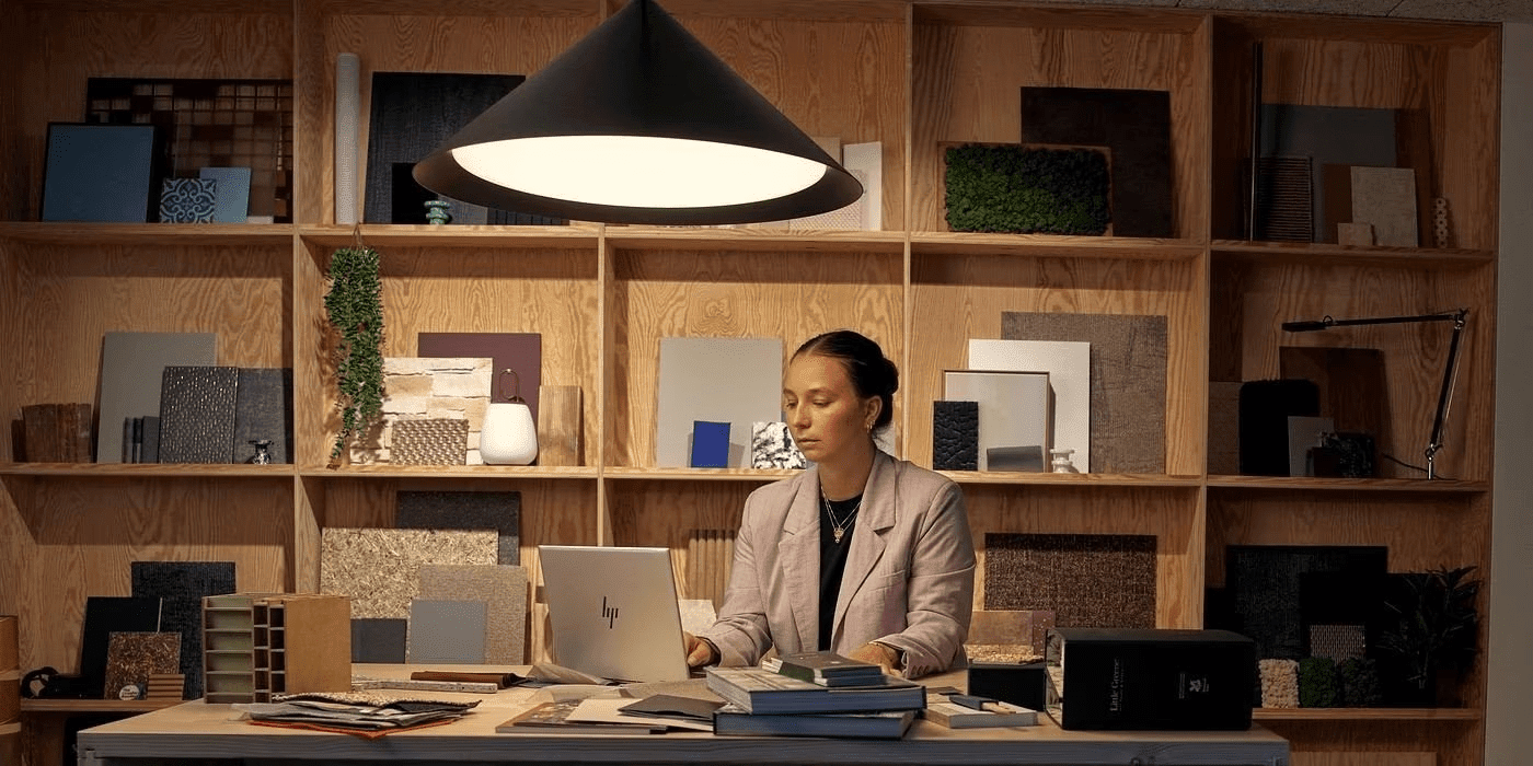 Mujer trabajando en una laptop, en una oficiana, y con condiciones de luz inapropiadas.